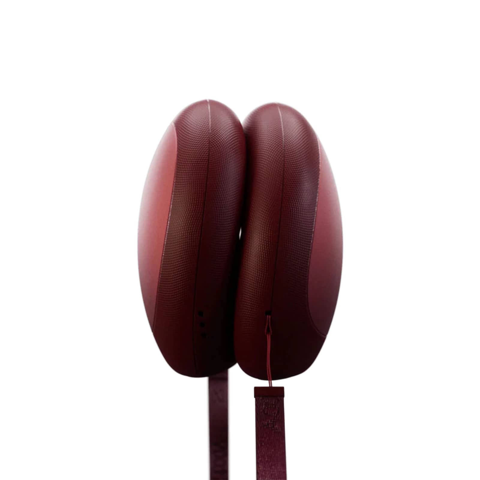 Die Stoons Handwärmer von Stoov sind zwei halbrunde Formen in einem dunklen Rot. An ihnen befestigt sind rote Gurte für die Handgelenke.