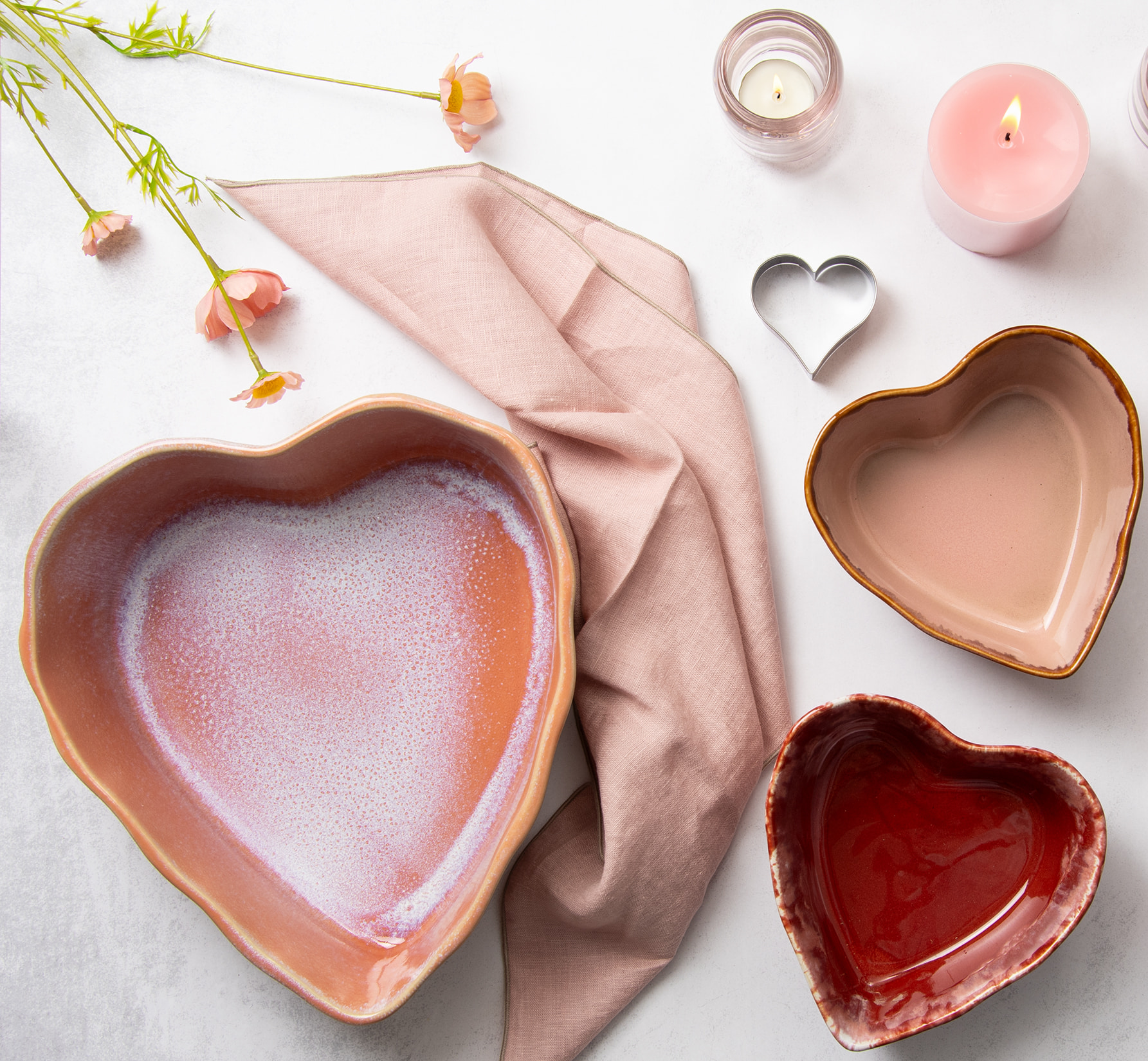 Eine große und zwei kleine Lisara Herzschüsseln von oben fotografiert. Auf dem Tisch befinden sich noch weitere Wohnaccessoires.