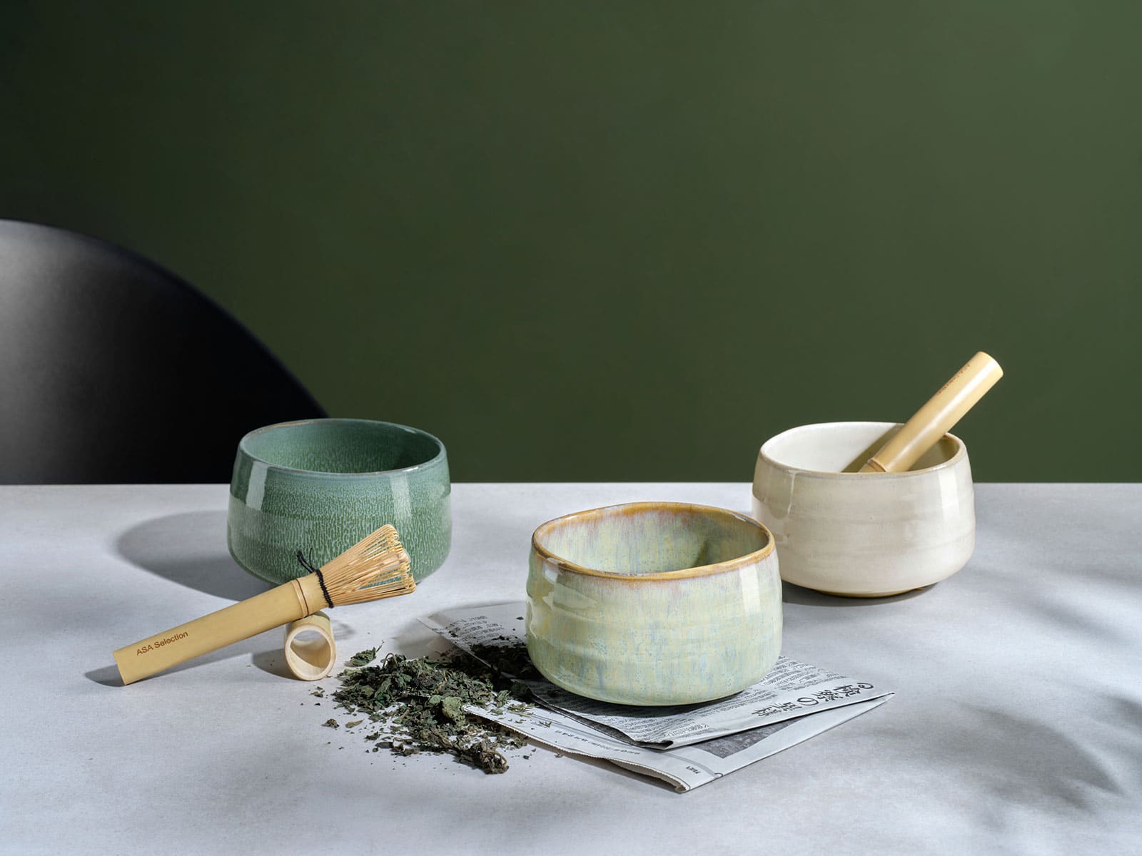 Auf einem weißen Tisch stehen drei Moribana Matcha Schalen neben den Werkzeugen, mit denen in diesen Schalen frischer Matcha zubereitet werden kann.